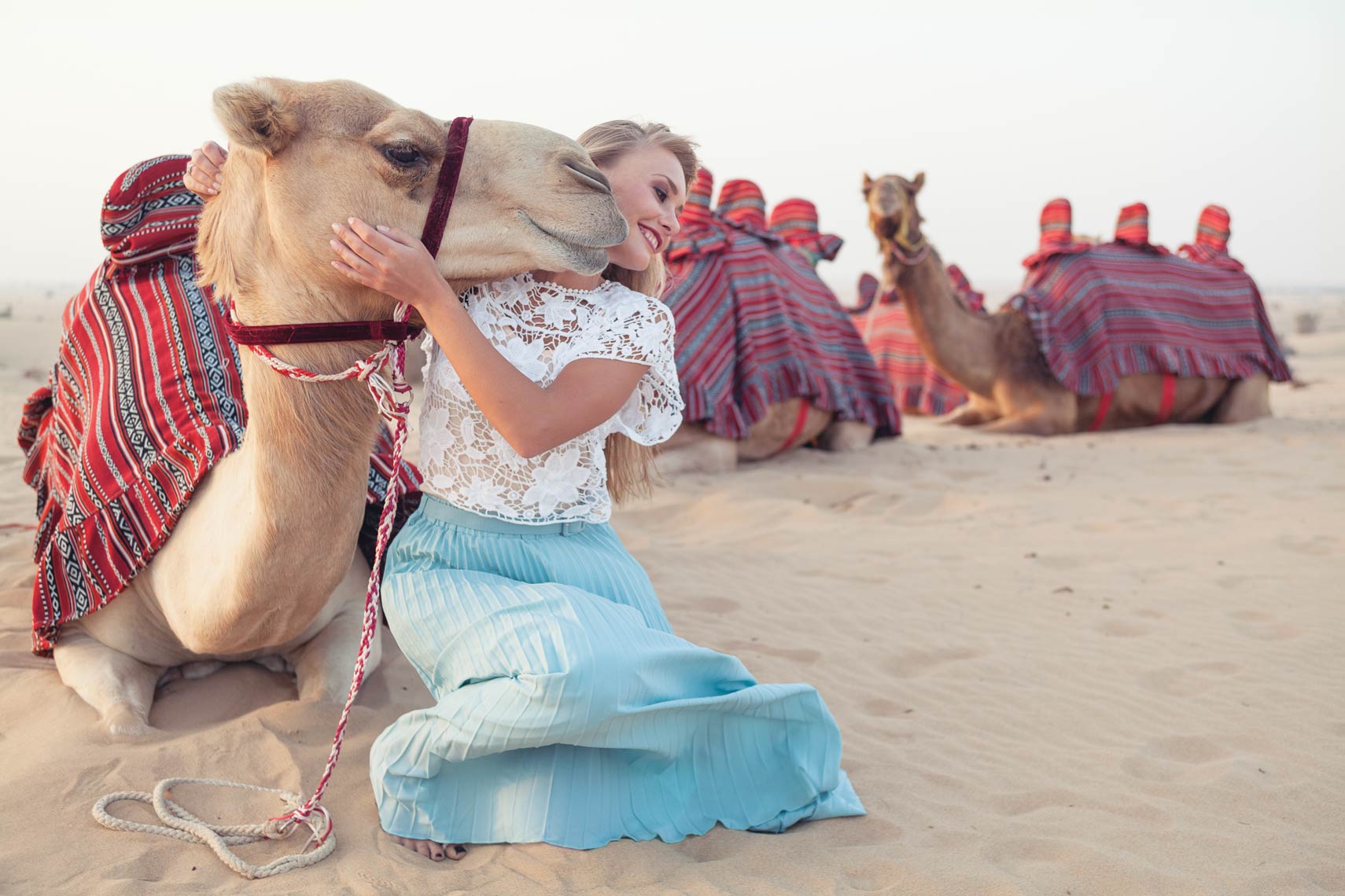 Fashion photography - woman with a camel kissing her face in the U.A.E. desert.