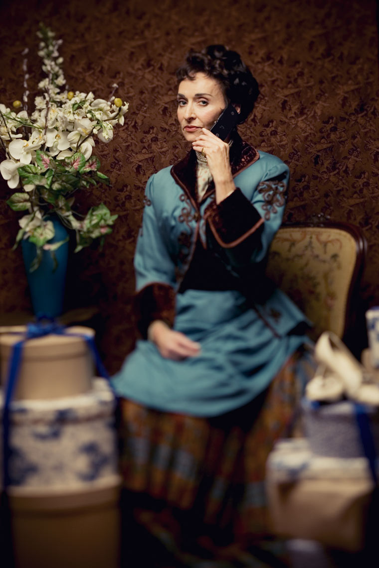 Woman in old dress with cellphone and packages looking like the Victorian era for Portland editorial photoshoot.