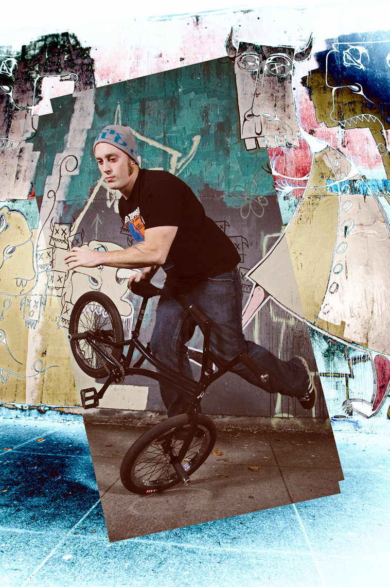 Man free riding on bike in front of wall mural of friendly monsters that have been solarized.