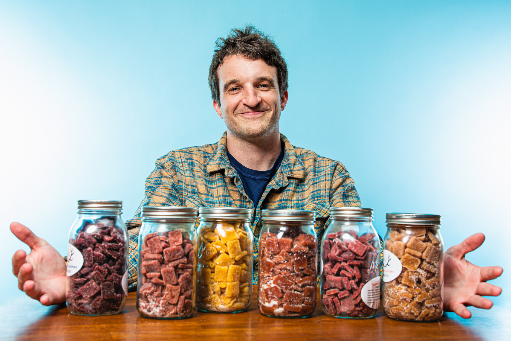 Editorial photograph Portland CEO - man with glass jars on table filled with gummies