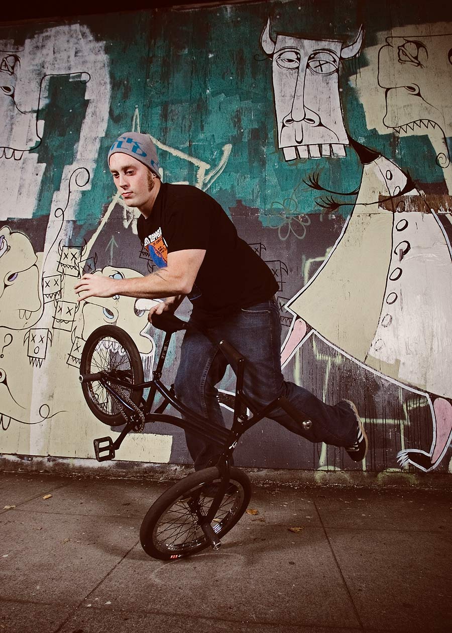 Free riding bicycle at night in front of wall mural of friendly looking monsters.