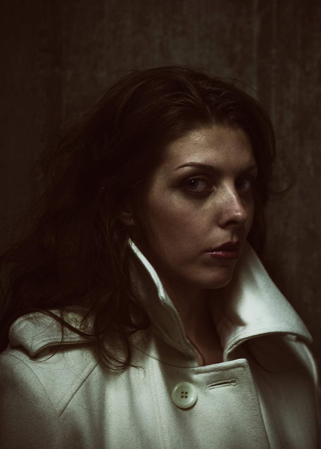 Moody portrait of woman in white coat in Portland Oregon studio. 