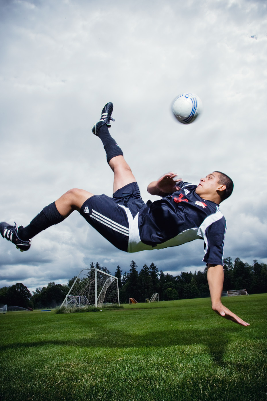Commercial photography of  soccer player doing a bicycle kick on a field with no other players around.