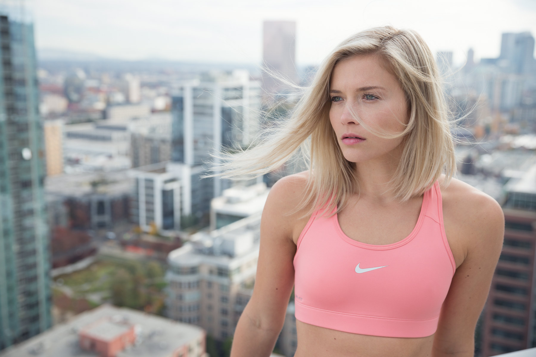 Commercial Photography Portland - woman in Nike sports bra on top of building with city skyline background