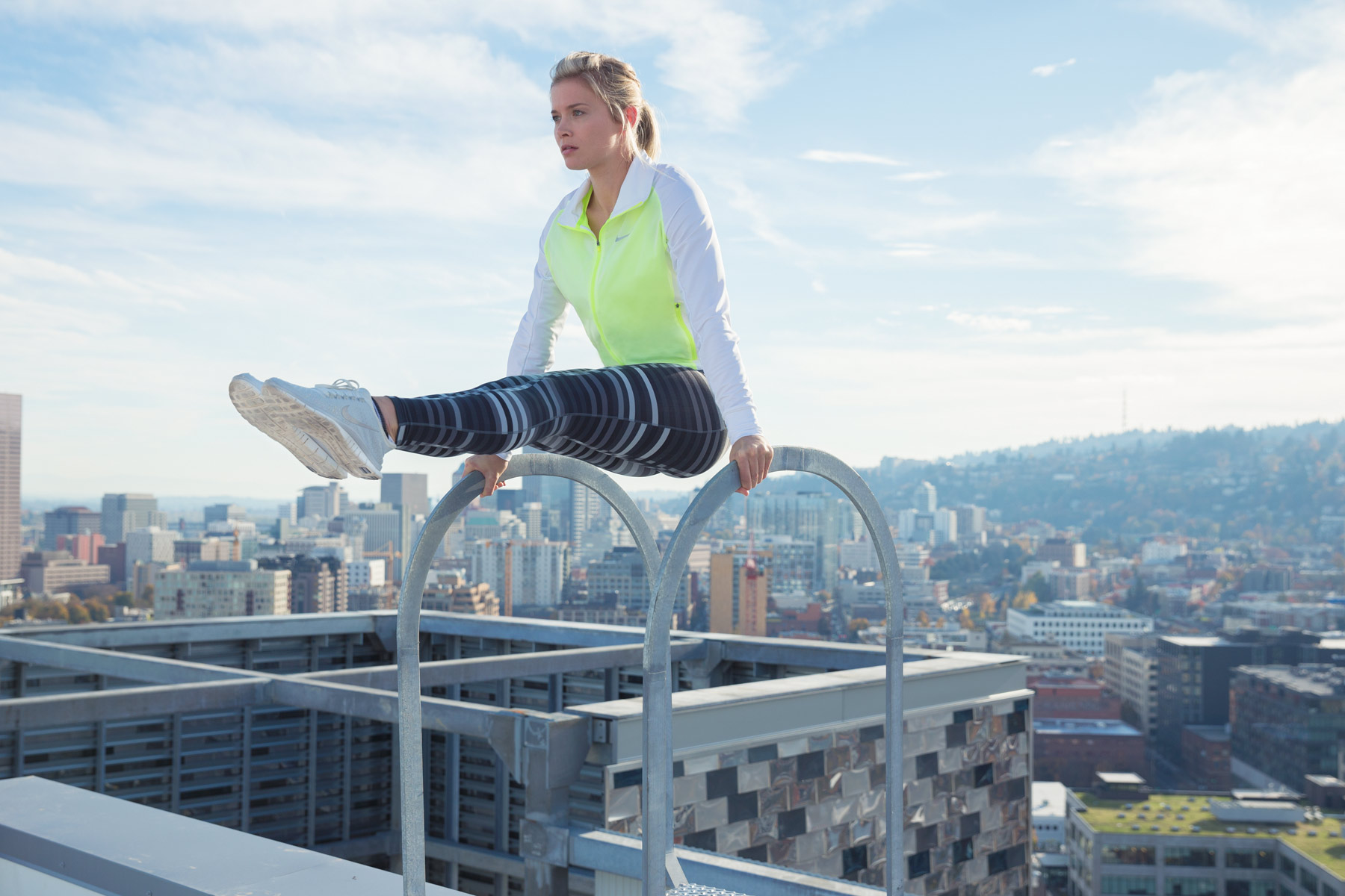 Advertising  photographer Portland - woman balancing on top of a building with Portland Oregon skyline behind her