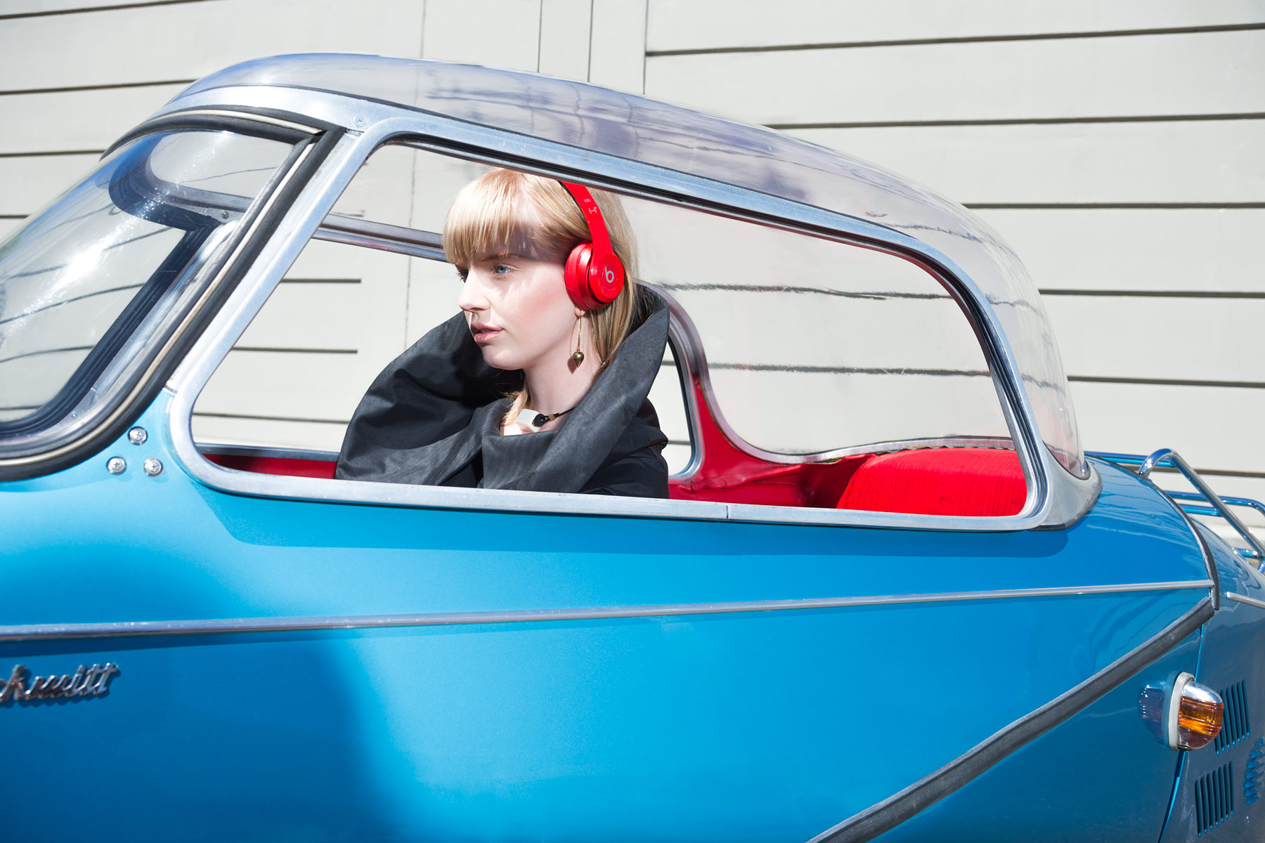 Commercial photography of woman in a Messerschmitt car wearing Beat headphones