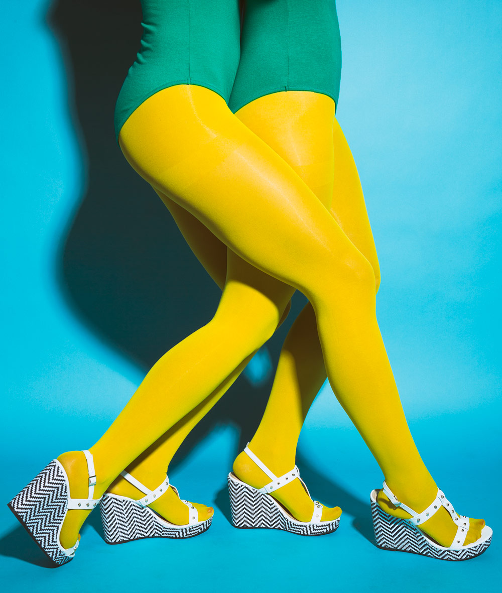 Four legs in yellow tights and four platform shoes on a blue background