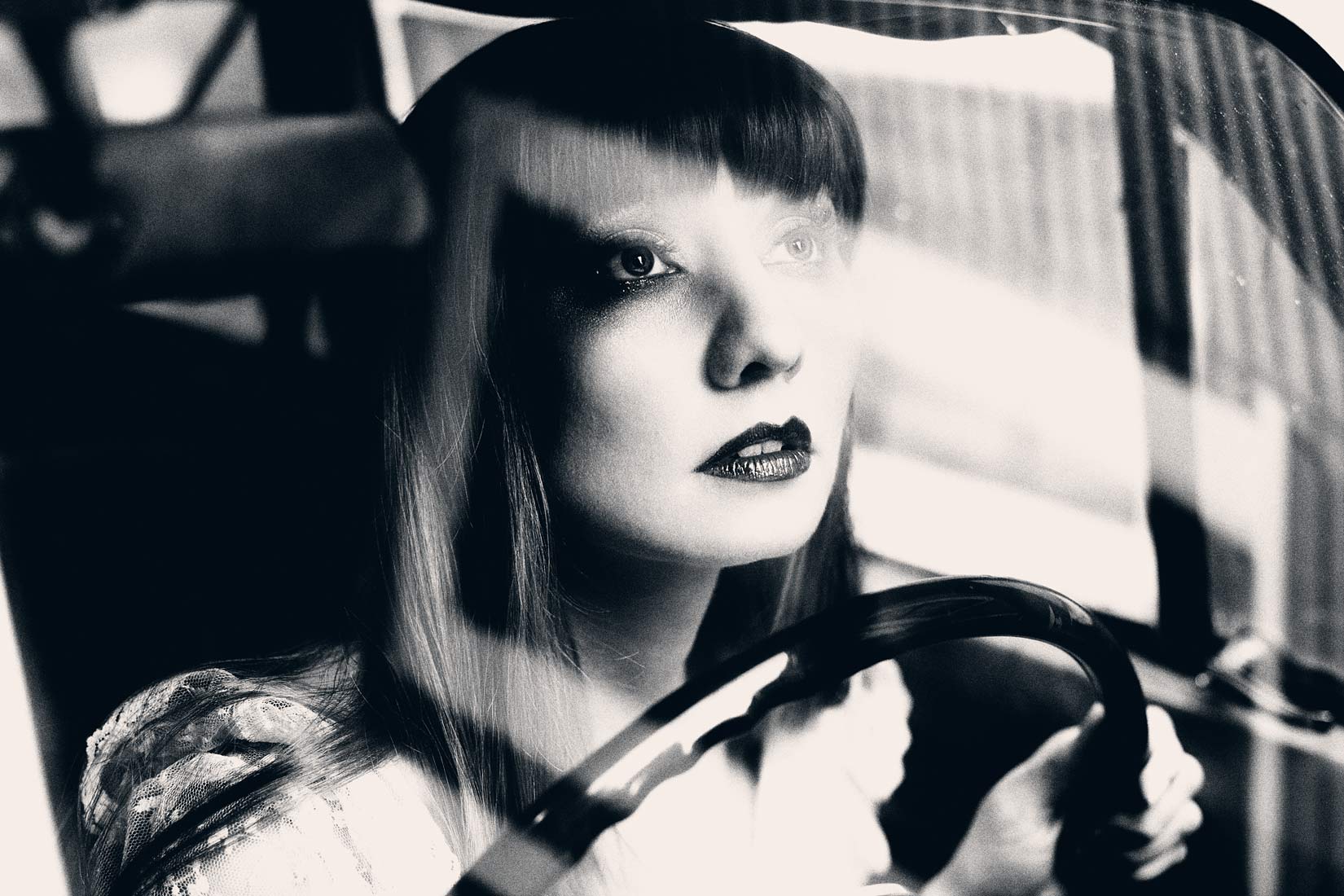Portrait looking through a windshield of a woman driving in black and white.