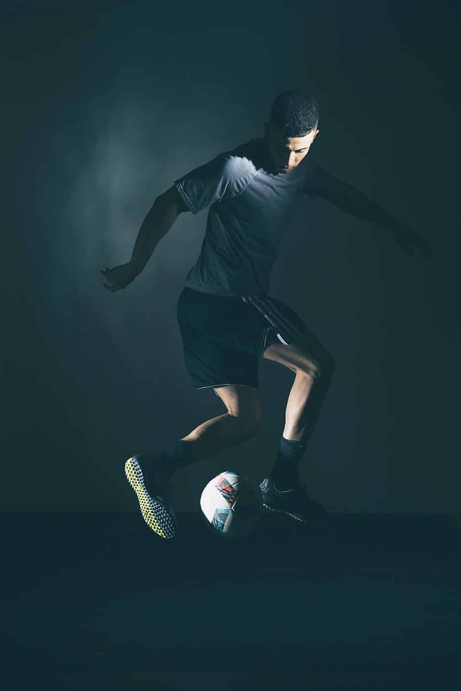 Commercial photographer Portland - man dribbling ball in dramatic light in dark studio setting