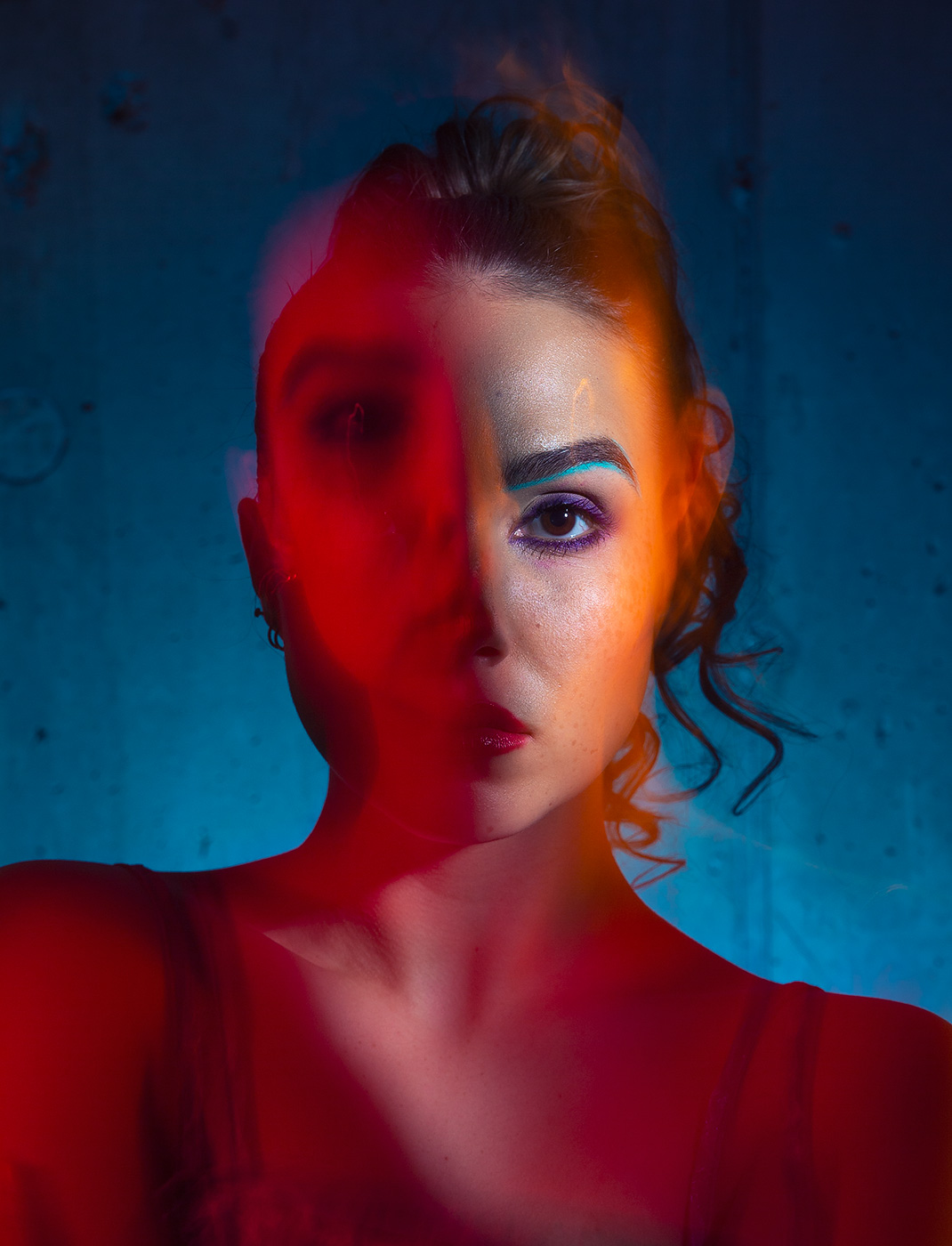 Colorful portrait of woman with distorted face by long exposure in reds and blues.