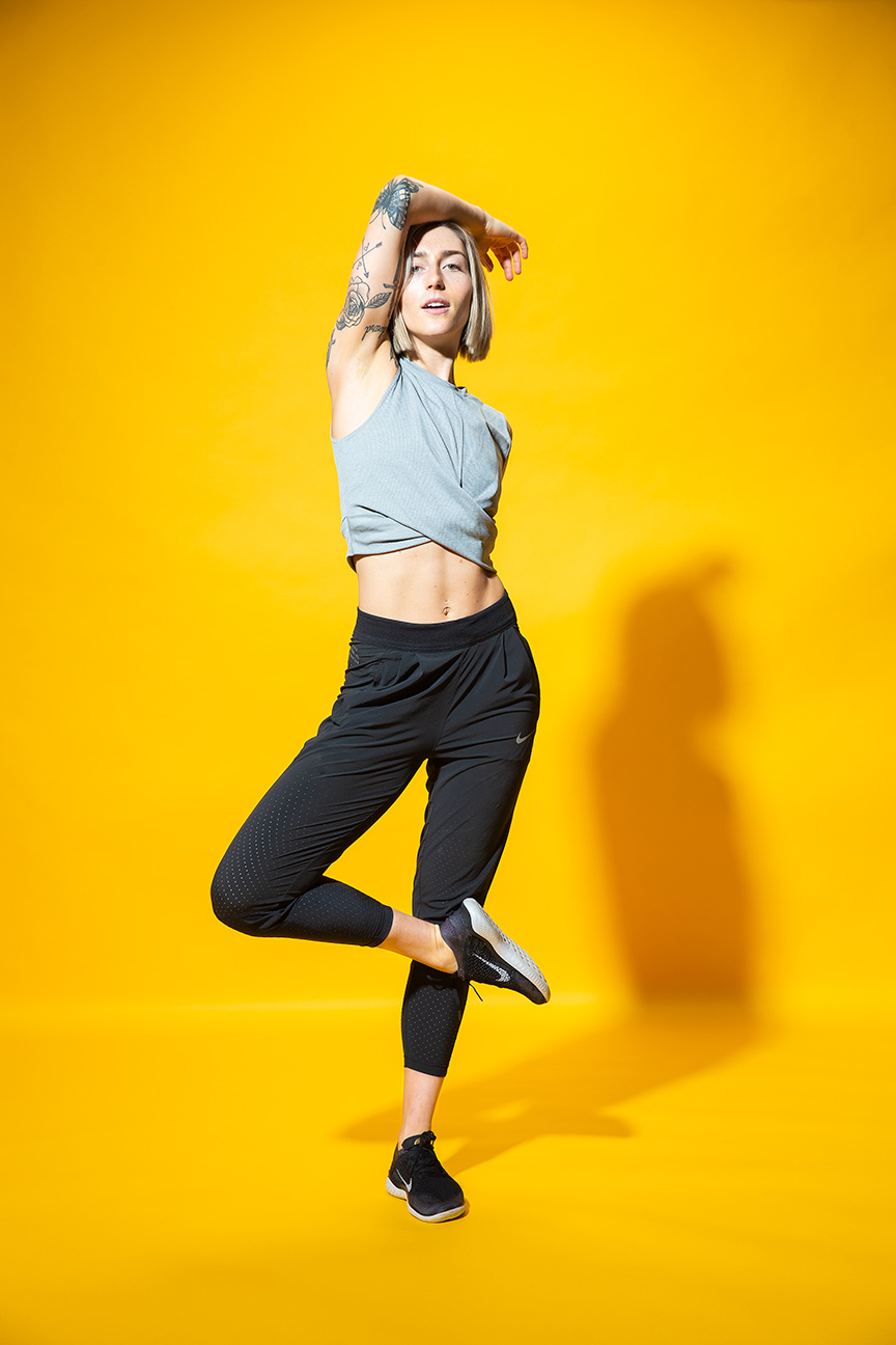 Advertising  photographer Portland - woman stretching wearing athletic clothing with orange background
